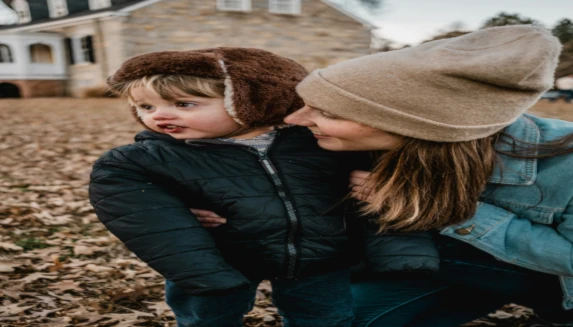 Women with little kid in a garden full of brown leaves 