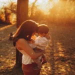 Women holding a little kid in a summer afternoon, in the park